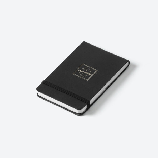 Svart anteckningsbok mot grå bakgrund.