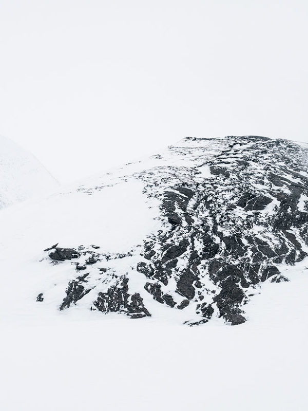 Snöig bergstopp med dimma.